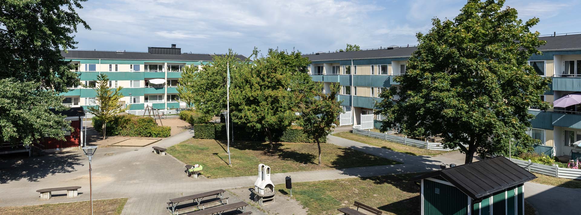 Turkost flerfamiljshus med grönskande innergörd.