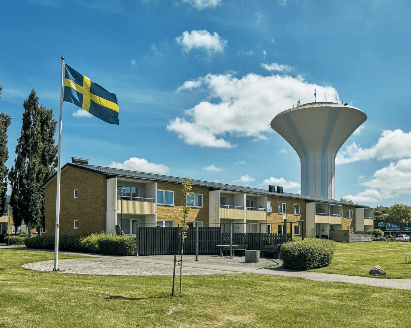 Svensk flagga vajar över tvåvåningshusen på Tulpanen i Bjuv