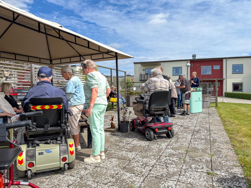 Hyresgäster på Falken i Bjuv samlade för midsommarfika på uteplatsen.