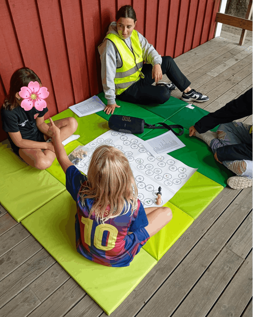 Barn spelar spel tillsammans med en aktivitetsledare under sommarlovsaktivitet på Årstiderna.