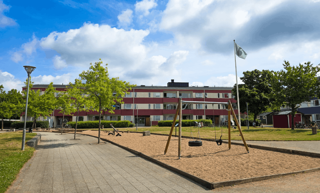 Lekplats och grönyta i bostadsområdet Årstiderna med flerfamiljshus i bakgrunden.
