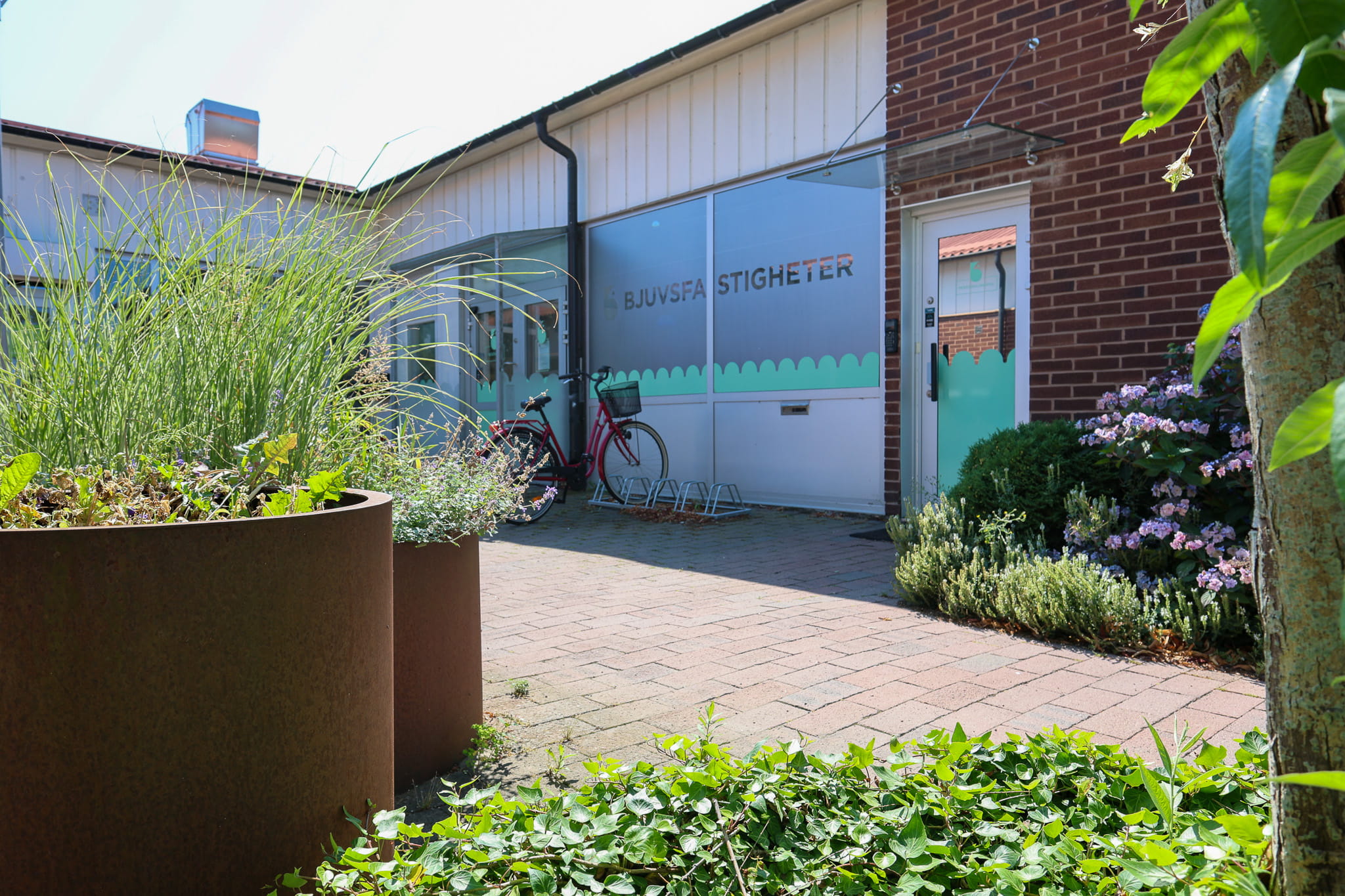 Entrén till Bjuvsfastigheters kontor, med växtlighet och cykelställ utanför.