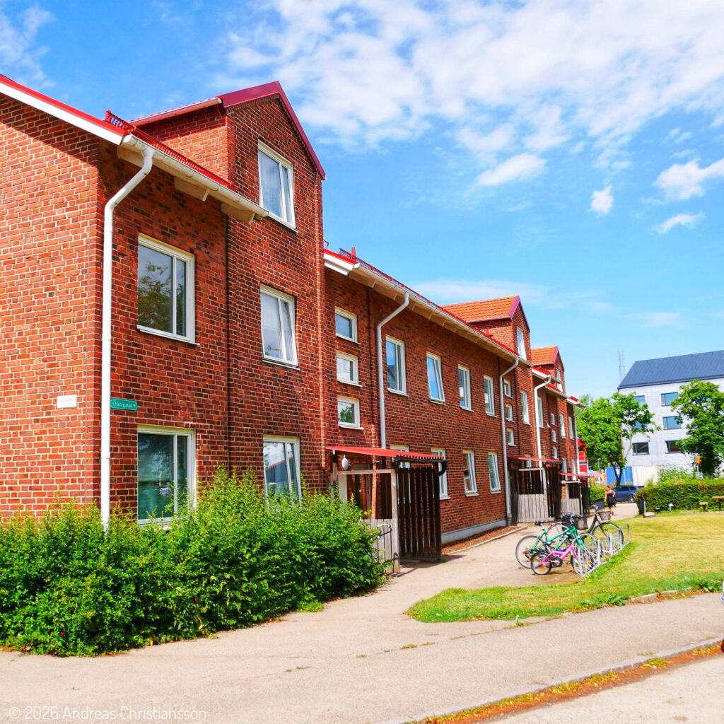 Rött tegelhus med uteplatser och grönska på Bjuvshem.