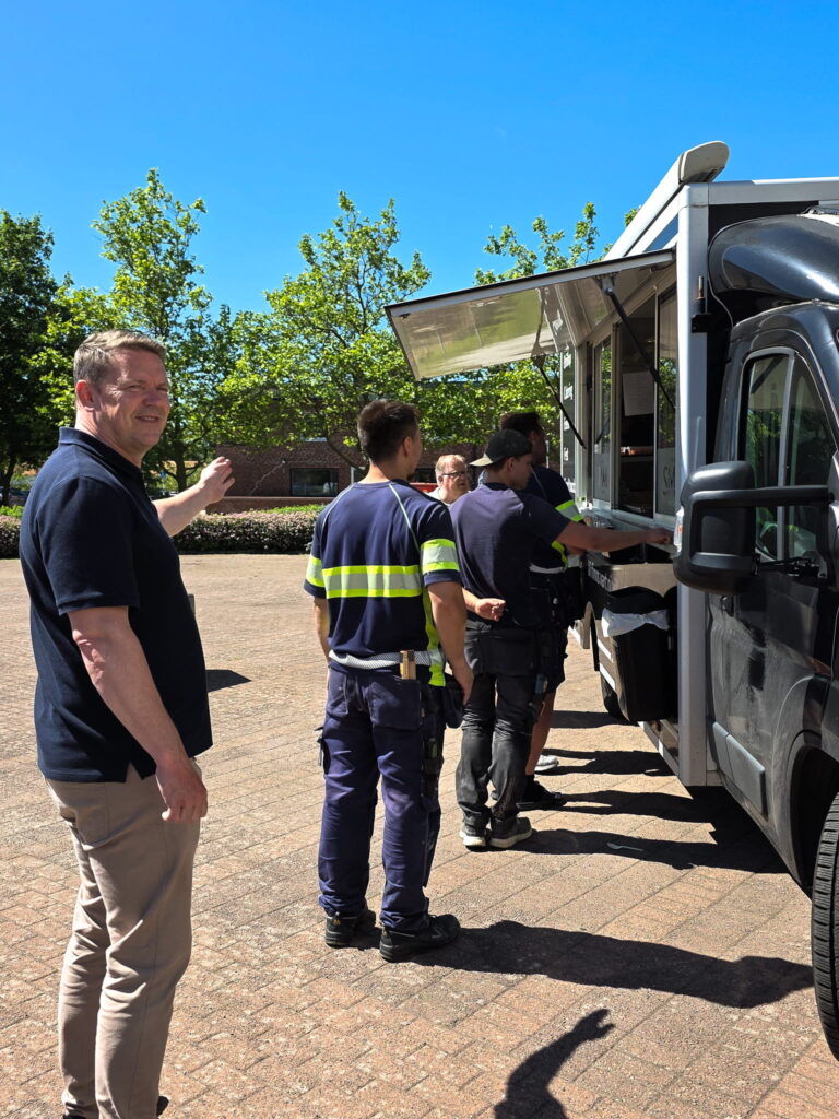Medarbetare och hantverkare köar vid en foodtruck utanför Bjuvsfastigheters bostadshus.