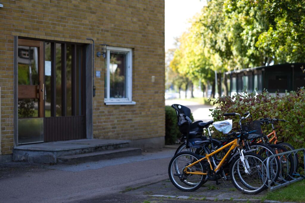 Entré till flerfamiljshus på Tulpanen med cyklar och grönska utanför.
