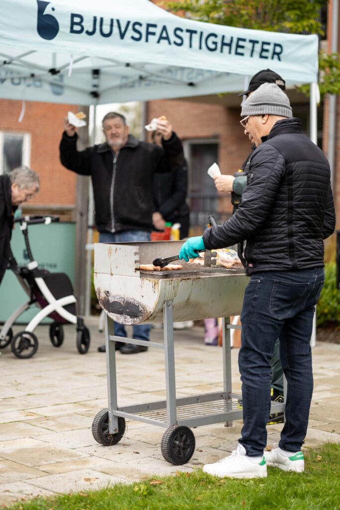 Korv grillas vid Bjuvsfastigheters tält under områdesaktivitet med hyresgäster på Akela.